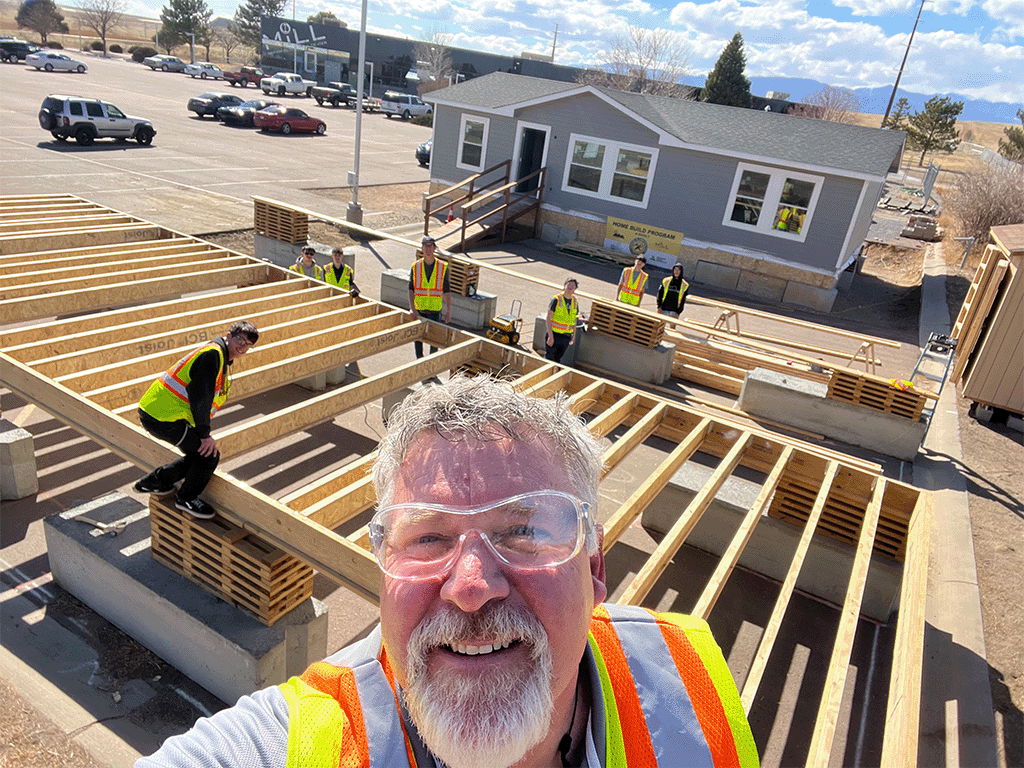 Careers in Construction Program. instructor taking selfie of himself and kids builing the foundation for a modular home