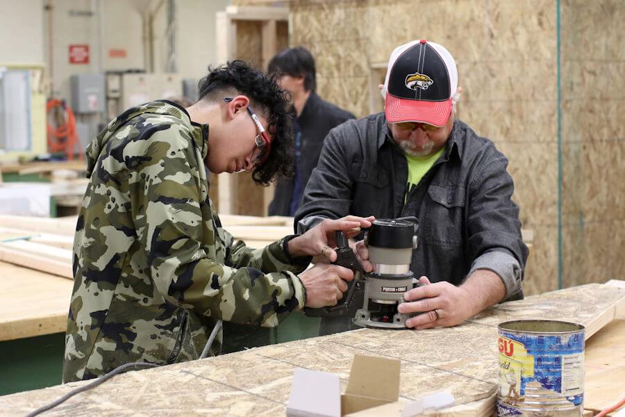 Student learning to use router with instructor